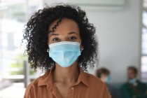Ritratto di donna di razza mista business creativo in piedi in un ufficio con indosso maschera. Salute e igiene sul luogo di lavoro durante la pandemia di Coronavirus Covid 19. — Foto stock