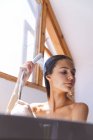 Femme caucasienne passant du temps à la maison, dans la salle de bain, se lavant les cheveux sous la douche. Distance sociale pendant le confinement en quarantaine du coronavirus Covid 19. — Photo de stock