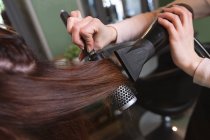 Mains de coiffeuse travaillant dans le salon de coiffure, séchage des cheveux de la cliente. Santé et hygiène sur le lieu de travail pendant la pandémie de Coronavirus Covid 19. — Photo de stock