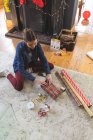 Кавказька жінка проводить час удома на Різдво, сидячи на підлозі біля каміна у вітальні, обгортаючи папір. Соціальна дистанція в Ковиді 19 Коронавірус карантин. — стокове фото