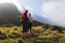 Casal sênior passando tempo na natureza juntos, andando nas montanhas, olhando para o mapa. atividade de aposentadoria saudável. — Fotografia de Stock