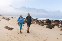 Старшая пара проводит время на природе вместе, гуляя по пляжу, разговаривая и смеясь. активный уход на пенсию. — стоковое фото