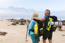 Coppia anziana trascorrere del tempo in natura insieme, passeggiando sulla spiaggia, l'uomo sta abbracciando donna. stile di vita sano attività pensionistica. — Foto stock