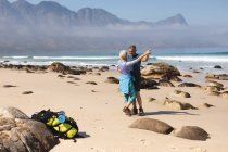 Старшая пара проводит время на природе вместе, гуляя по пляжу, танцуя. активный уход на пенсию. — стоковое фото
