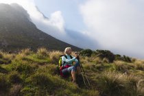 Seniorin, die Zeit in der Natur verbringt, in den Bergen spazieren geht, im Gras sitzt und die Aussicht genießt. Gesunder Lebensstil im Ruhestand. — Stockfoto