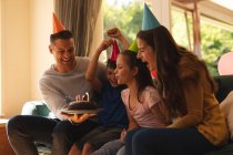 Kaukasische Familie, die zu Hause zusammen einen Geburtstag feiert, Partyhüte trägt und Kerzen bläst. Qualität der gemeinsamen Zeit bei Coronavirus covid 19 Quarantäne Lockdown. — Stockfoto