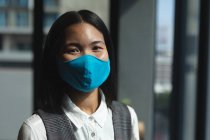 Porträt einer asiatischen Frau mit Gesichtsmaske im modernen Büro. Soziale Distanzierung von Quarantäne während der Coronavirus-Pandemie — Stockfoto
