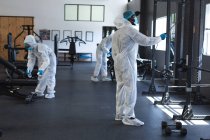 Ein Team von Arbeitern in Schutzkleidung und Mundschutz reinigt die Turnhalle mit Desinfektionsmittel. Soziale Distanzierung von Quarantäne während der Coronavirus-Pandemie — Stockfoto