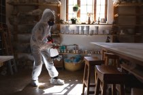 Caucasian male cleaner in protective clothes working in pottery studio. disinfecting the whole place. small creative business during covid 19 coronavirus pandemic. — Stock Photo