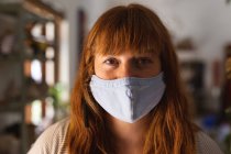 Portrait of caucasian woman wearing face mask at pottery studio. small creative business during covid 19 coronavirus pandemic. — Stock Photo
