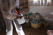 Pulitore maschio caucasico in abiti protettivi che lavora in studio di ceramica. disinfettare tutto il posto. piccola attività creativa durante covid 19 coronavirus pandemia. — Foto stock