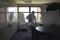 Trabajador de la salud que usa ropa protectora en la oficina usando desinfectante. limpieza y desinfección prevención y control de la epidemia de covid-19 - foto de stock