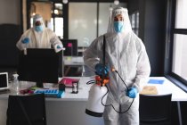 Portrait of male health worker at modern office. wearing face mask and protective clothes carrying disinfectant spray. cleaning and disinfection prevention and control of covid-19 epidem — Stock Photo