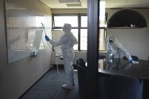 Команда медицинских работников, носящих защитную одежду уборка офиса с использованием дезинфицирующего средства. очистка и дезинфекция профилактика и контроль эпидемии ковида-19 — стоковое фото