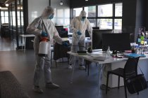 Equipo de trabajadores de la salud que usan ropa protectora en la oficina usando desinfectante. limpieza y desinfección prevención y control de la epidemia de covid-19 - foto de stock