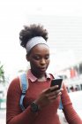 Retrato de mulher afro-americana usando um smartphone na rua e sobre a cidade durante a pandemia de coronavírus covid 19. — Fotografia de Stock