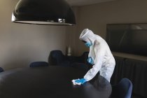 Trabajador de la salud que usa ropa protectora en la oficina usando spray desinfectante y tela. limpieza y desinfección prevención y control de la epidemia de covid-19 - foto de stock