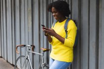 Femme afro-américaine utilisant un smartphone dans une rue de la ville pendant la pandémie de coronavirus 19 covid. — Photo de stock