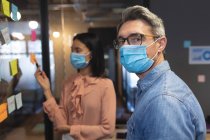 Portrait of caucasian man wearing face mask standing in modern office. social distancing quarantine lockdown during coronavirus pandemic — Stock Photo