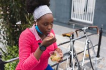 African american woman eating a salad on street out and about in the city during covid 19 coronavirus pandemic. — Stock Photo