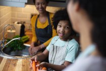 Mixed race lesbian couple and daughter preparing food in kitchen. self isolation quality family time at home together during coronavirus covid 19 pandemic. — Stock Photo