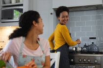 Mixed race lesbian couple preparing food in kitchen. self isolation quality family time at home together during coronavirus covid 19 pandemic. — Stock Photo