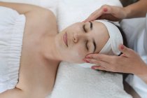 Femme blanche allongée tandis que l'esthéticienne lui donne un visage. client bénéficiant d'un traitement dans un salon de beauté. — Photo de stock