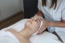 Caucasian woman lying back while beautician gives her a facial. customer enjoying treatment at a beauty salon. — Stock Photo