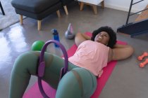 Afroamerikanerin liegt auf Gymnastikmatte beim Training. Selbst-Isolation Fitness zu Hause während Coronavirus covid 19 Pandemie. — Stockfoto