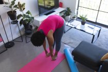African american woman standing on exercise mat working out. self isolation fitness at home during coronavirus covid 19 pandemic. — Stock Photo