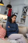Жінка змішаної раси, що сидить на дивані, виглядає сумно. самоізоляція якість сімейного часу вдома разом під час пандемії коронавірусу 19 . — стокове фото