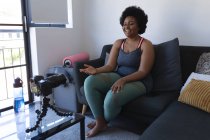 Африканская американка-блогер записывает видео. о тренировках. самоизоляция технологии связи в домашних условиях во время коронавируса ковид 19 пандемии. — стоковое фото