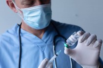 Kaukasischer Arzt mit Mundschutz und Füllspritze. medizinisches Fachpersonal Hygiene während Coronavirus covid 19 Pandemie. — Stockfoto