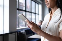 Donna d'affari razza mista in piedi utilizzando tablet digitale in ufficio moderno. affari ufficio moderno tecnologia sul posto di lavoro. — Foto stock