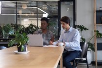 Різноманітні бізнесмени сидять, використовуючи ноутбук, що проходить через паперові роботи в сучасному офісі. бізнес сучасні технології офісного робочого місця . — стокове фото