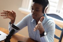Mujer afroamericana usando auriculares usando micrófono y portátil. comunicación en línea, permanecer en casa en aislamiento durante el bloqueo de cuarentena. - foto de stock