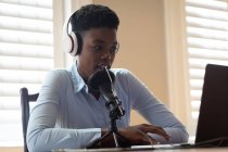 Африканская американка в наушниках с микрофоном и ноутбуком. общение онлайн, оставаясь дома в самоизоляции во время карантинной изоляции. — стоковое фото