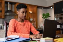 Mulher afro-americana usando laptop na cozinha. ficar em casa em auto-isolamento durante o confinamento de quarentena. — Fotografia de Stock