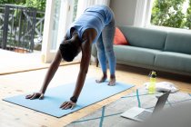 Африканская американка выполняет упражнения на растяжку дома. оставаться дома в изоляции в карантинной изоляции — стоковое фото