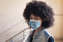 Смешанная расовая женщина в маске с лозунгом, смотрящая в камеру. Концепция гендерного расового равенства. — стоковое фото