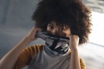 Femme de race mixte mettant un masque facial en regardant la caméra. genre fluide identité lgbt concept d'égalité raciale. — Photo de stock