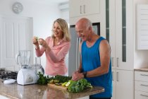 Homem e mulher caucasianos sênior preparando bebidas de saúde de frutas e vegetais. bem-estar fitness na casa de cuidados sênior. — Fotografia de Stock