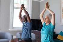 Senioren-Mixed-Race-Paar in Sportkleidung beim Training im Wohnzimmer. Während der Quarantäne zu Hause bleiben und sich selbst isolieren. — Stockfoto