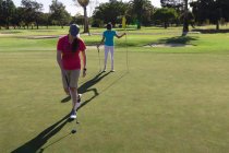 Duas mulheres caucasianas a jogar golfe, uma a tirar a bandeira do buraco. esporte lazer hobbies golfe saudável ao ar livre estilo de vida. — Fotografia de Stock