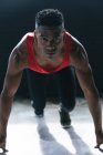 African american man wearing sports clothes kneeling starting to run in empty urban building. urban fitness healthy lifestyle. — Stock Photo