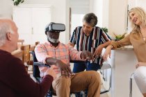 Senior caucasian and african american couples sitting on couch using vr headset at home. senior retirement lifestyle friends socializing. — Stock Photo