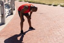 Ajuste o homem americano africano sênior que usa fones de ouvido exercitando-se no sol recuperando o fôlego. esporte de aposentadoria saudável ao ar livre fitness lifestyle. — Fotografia de Stock
