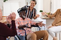 Ältere kaukasische und afrikanisch-amerikanische Paare, die zu Hause auf der Couch sitzen und ihr Headset benutzen. Senioren-Lebensstil Freunde Geselligkeit. — Stockfoto
