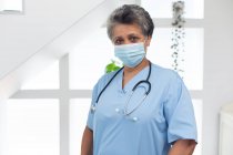 Portrait of senior african american female doctor wearing a face mask looking at the camera. healthcare hygiene protection during coronavirus covid 19 pandemic. — Stock Photo