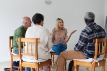 Groupe diversifié d'aînés qui parlent pendant une séance de thérapie de groupe à la maison. santé fitness bien-être au foyer de soins pour personnes âgées. — Photo de stock